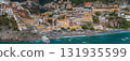 View of Positano on Italy's Amalfi Coast, with stacked buildings, Chiesa di Santa Maria Assunta, a lively beach, and turquoise Tyrrhenian Sea waters. 131935599