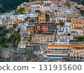 View of Positano's cascading buildings in vibrant colors, with terraces overlooking the sea and a small beach area at the base of the hillside. 131935600