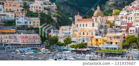 Positano on Italy's Amalfi Coast features stacked buildings, the Church of Santa Maria Assunta, a beach with boats and umbrellas, and lush cliffs. Positano on Italy's Amalfi Coast features stacked buildings, the Church of Santa Maria Assunta, a beach with boats and umbrellas, and lush cliffs. 131935607