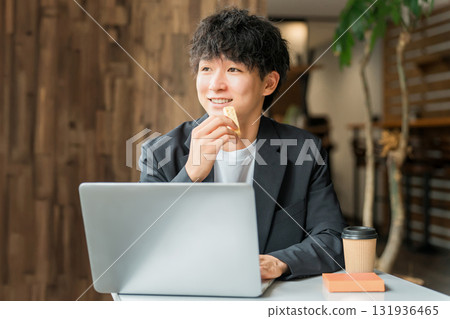 A businessman/man working on a computer while having a snack at a cafe A businessman/man working on a computer while having a snack at a cafe 131936465