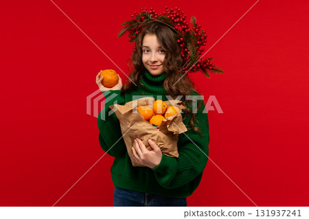 Young girl in green sweater holding oranges in paper bag Young girl in green sweater holding oranges in paper bag 131937241