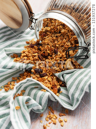 Granola pouring from jar on striped cloth 131937278
