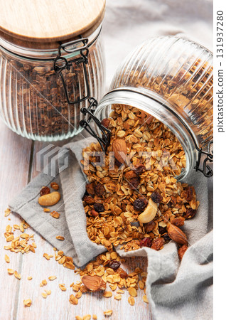 Granola mix with oats, nuts, and dried fruits spilling onto a grey napkin Granola mix with oats, nuts, and dried fruits spilling onto a grey napkin 131937280