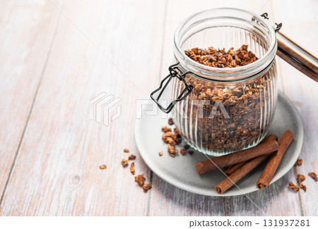 Granola cereal in glass jar with cinnamon sticks Granola cereal in glass jar with cinnamon sticks 131937281