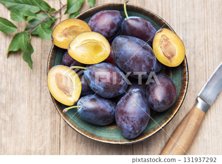 Fresh ripe plums in bowl on wood surface Fresh ripe plums in bowl on wood surface 131937292