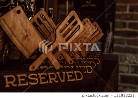 wooden reserved signs designed as cooking utensils in cozy restaurant during evening hours. closeup. wooden reserved signs designed as cooking utensils in cozy restaurant during evening hours. closeup. 131938221
