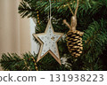 decorative wooden star and pine cone ornament hanging on Christmas tree in holiday season. closeup. 131938223
