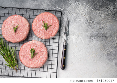 Close up of a juicy raw meat patty cutlet, ideal for crafting mouthwatering sandwiches and savory dishes. white background. top view Close up of a juicy raw meat patty cutlet, ideal for crafting mouthwatering sandwiches and savory dishes. white background. top view 131939947