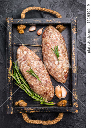 Raw kebabs or kabaps on wooden tray, beautifully arranged and ready to be cooked for a delicious outdoor feast. black background. top view 131939949