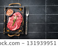 Marbled raw Rib eye steak with herbs in wooden tray, fresh beef meat. black kitchen background. top view 131939951