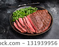 Juicy grilled top sirloin on a plate, accompanied by seasonal greens for a delicious meal. black background. top view 131939956