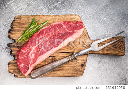 Uncooked striploin steak or strip New York on a wooden cutting board, inviting you to create mouthwatering recipes for any occasion. white background. top view 131939958
