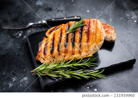 Grilled chicken breasts steaks with rosemary, farm poultry meat, top view, black background. 131939960
