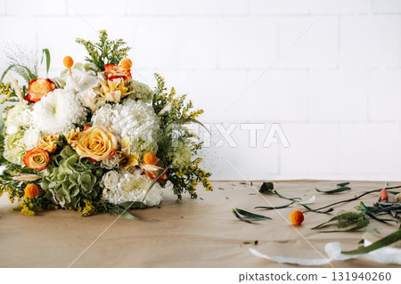 Completed autumn bouquet placed on a craft table with ribbon rolls nearby. Eco-friendly holiday decor, biodegradable florals, rustic seasonal arrangement, sustainable gifting 131940260