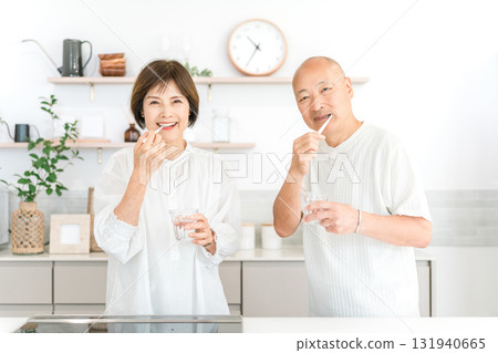 Senior couple brushing their teeth in the kitchen (dental care, bad breath care) 131940665