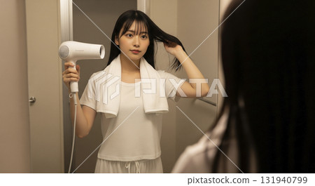 洗完澡後，她穿著家居服，用吹風機吹乾頭髮。 131940799