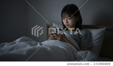 A woman lying on the bed in her loungewear and operating her smartphone 131940809