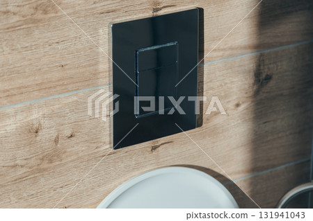 Close-up of a chrome dual flush button on a wall with wood-grain tiles Close-up of a chrome dual flush button on a wall with wood-grain tiles 131941043