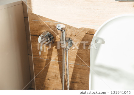 Hygiene bidet shower on wall near toilet in house 131941045