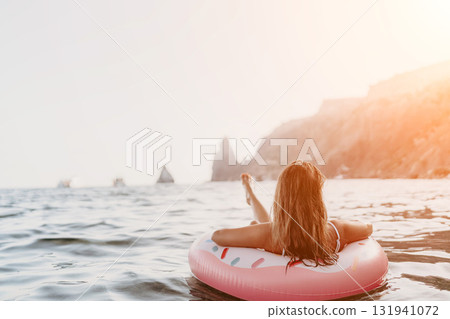 Woman, floating, ocean. Relaxing on a donut ring under bright sun near scenic cliffs with copy space. Woman, floating, ocean. Relaxing on a donut ring under bright sun near scenic cliffs with copy space. 131941072