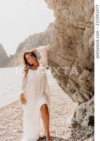 Woman White Dress Beach Rock - A woman wearing a white dress stands by a rocky cliff on a beach. Woman White Dress Beach Rock - A woman wearing a white dress stands by a rocky cliff on a beach. 131941077