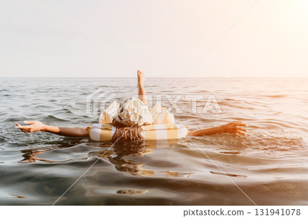 Woman Float Ocean Inflatable Summer - A young woman floats on an inflatable ring in the ocean on a summer day. 131941078
