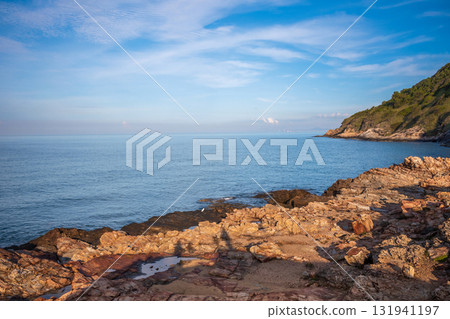 Beautiful seascape at Khao Laem Ya in Rayong, Thailand, featuring golden-brown rocks along the shoreline and lush green cliffs under a clear blue sky Beautiful seascape at Khao Laem Ya in Rayong, Thailand, featuring golden-brown rocks along the shoreline and lush green cliffs under a clear blue sky 131941197