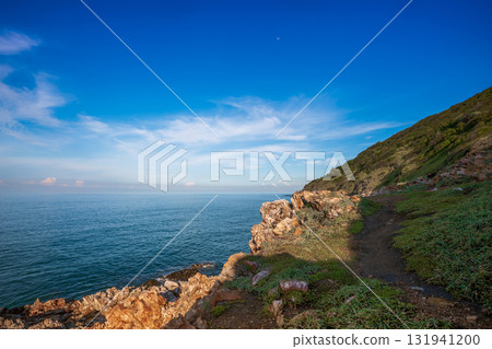Dramatic coastal cliff view at Khao Laem Ya in Rayong, Thailand, showcasing rugged red rocks, and the vast blue ocean under a bright sky Dramatic coastal cliff view at Khao Laem Ya in Rayong, Thailand, showcasing rugged red rocks, and the vast blue ocean under a bright sky 131941200