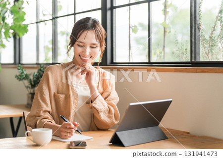 A woman doing nomadic work while drinking coffee at a cafe 131941473