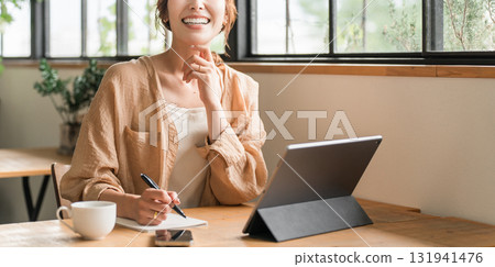 A woman doing nomadic work while drinking coffee at a cafe A woman doing nomadic work while drinking coffee at a cafe 131941476