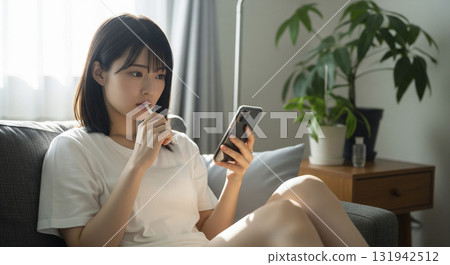 Morning. Sitting on the sofa, brushing my teeth while looking at my smartphone 131942512