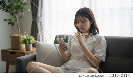 Morning. Sitting on the sofa, brushing my teeth while looking at my smartphone 131942513