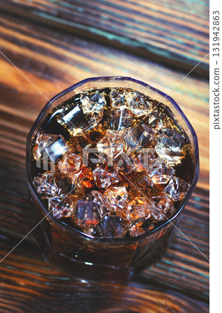 Whiskey and cola in a glass glass with ice on the table Whiskey and cola in a glass glass with ice on the table 131942863