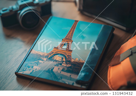 Travel guide featuring the Eiffel tower is lying on a table next to cameras and a backpack, suggesting an upcoming trip to Paris Travel guide featuring the Eiffel tower is lying on a table next to cameras and a backpack, suggesting an upcoming trip to Paris 131943432