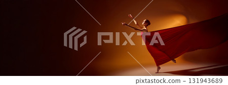 Female dancer in red fabric performing graceful motion on orange stage background. Banner Female dancer in red fabric performing graceful motion on orange stage background. Banner 131943689
