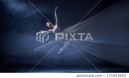 Ballet dancer suspended in stretched fabric performing stage leap 131943693