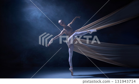 Ballet dancer standing en pointe wrapped in fabric under blue stage light Ballet dancer standing en pointe wrapped in fabric under blue stage light 131943714