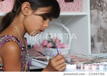 A girl paints a picture using paints and a brush. Paint by numbers. A girl paints a picture using paints and a brush. Paint by numbers. 131943760