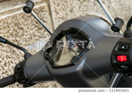 A close-up view of a motorcycle scooters speedometer and handlebars 131945003