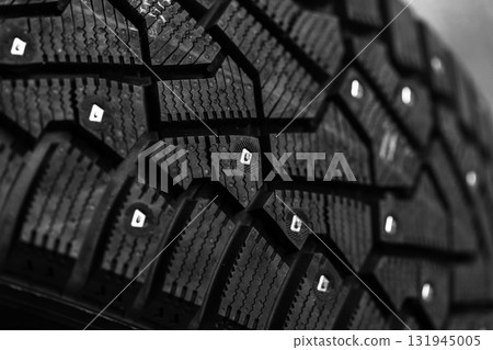 A brand new black studded car tire with metal studs embedded within the tread 131945005