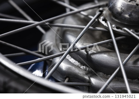 A detailed close-up view of a moto wheel hub, showcasing spokes, rim, and axle A detailed close-up view of a moto wheel hub, showcasing spokes, rim, and axle 131945021