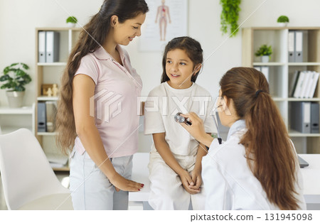 Pediatrician examining child with mother during clinic checkup using stethoscope Pediatrician examining child with mother during clinic checkup using stethoscope 131945098
