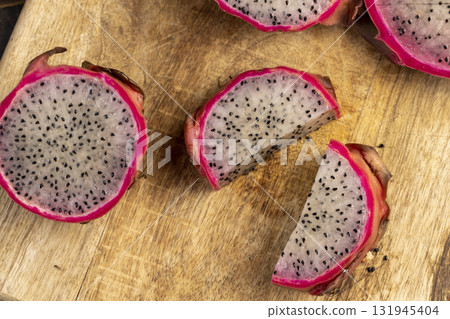 ripe red pitaya cut in half with lots of small black seeds and white sweet flesh inside, sweet ripe dragon fruit with black small seeds and light flesh cut in half ripe red pitaya cut in half with lots of small black seeds and white sweet flesh inside, sweet ripe dragon fruit with black small seeds and light flesh cut in half 131945404