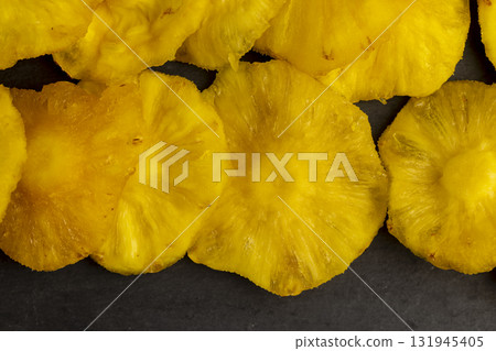 dried ripe bright yellow pineapple on a black slate board, cut into rings and dried yellow clean slices of ripe pineapple for long-term storage and used as a sweet dried ripe bright yellow pineapple on a black slate board, cut into rings and dried yellow clean slices of ripe pineapple for long-term storage and used as a sweet 131945405
