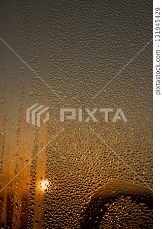 water droplets from condensation on the window glass at sunset, wet glass with water droplets on the background of an orange sky out of focus at sunset water droplets from condensation on the window glass at sunset, wet glass with water droplets on the background of an orange sky out of focus at sunset 131945429