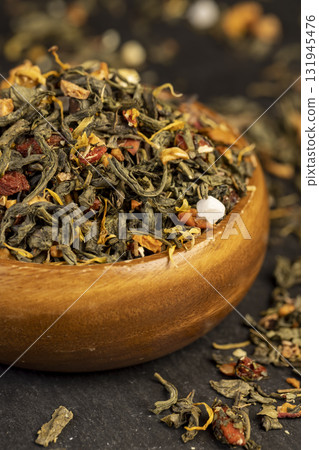 large-leaved green tea poured into a wooden cup with the addition of fruits and berries, high-quality expensive tea in a wooden bowl large-leaved green tea poured into a wooden cup with the addition of fruits and berries, high-quality expensive tea in a wooden bowl 131945476