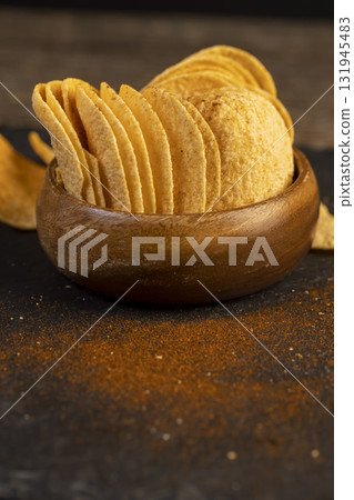 crispy potato chips fried in oil and sprinkled with spices of dried red sweet pepper, a large number of delicious salty sweet chips with aromatic spices 131945483