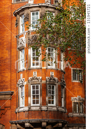 Red brick Edwardian building with ornate bay windows and decorative stone details in London Red brick Edwardian building with ornate bay windows and decorative stone details in London 131945721
