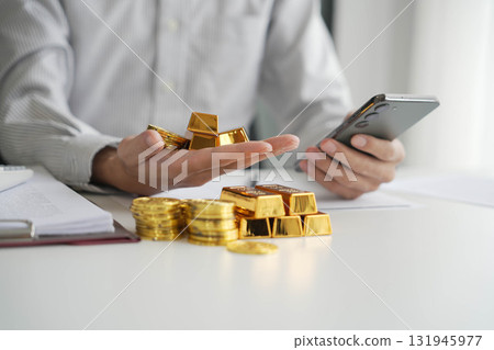 Gold Trading Businessman invest in trading gold, calculating profit price of gold in stock market when price rising rapidly, using phone monitoring gold price in stock market. Gold Trading Businessman invest in trading gold, calculating profit price of gold in stock market when price rising rapidly, using phone monitoring gold price in stock market. 131945977