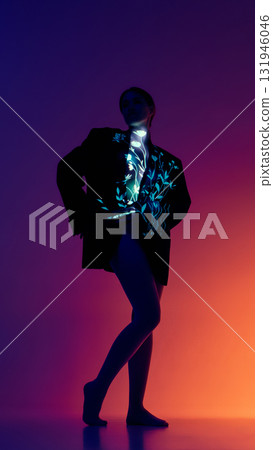 Full body portrait of woman with glowing floral projection on suit in orange purple light 131946046